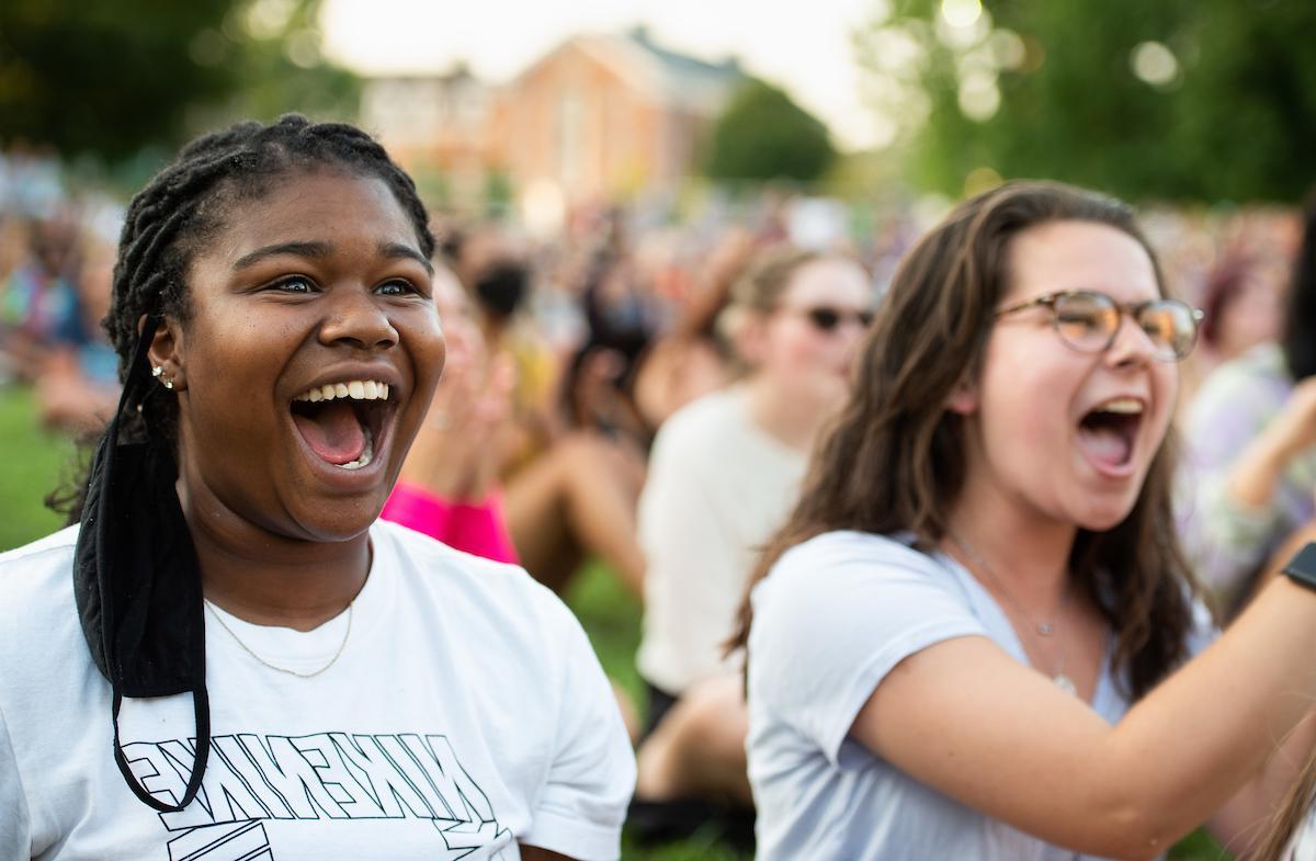 Two girls smile in an outdoor crowd